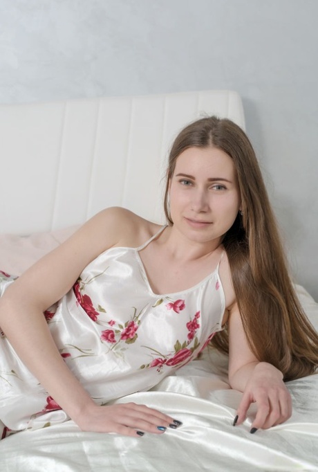 Den langhårede teenager Lady Di smider satinundertøjet og poserer nøgen på en seng