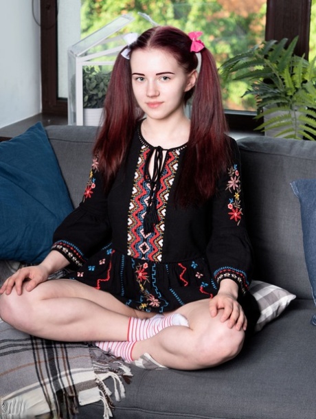 Unga snygga Polina klär av sig till strumporna på en soffa i flätor