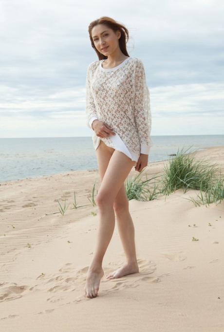 Jonge schoonheid Lena Raz wordt volledig naakt op een zandstrand