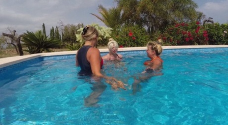 Eldre blond Sweet Susi og en venninne runker en fyrs pikk under vann i et basseng.