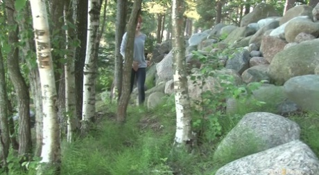 Natuurlijke roodharige Ira neemt een broodnodige plas op rotsblokken in het bos