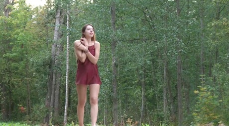 Den beniga tjejen Diana Sweet placerar en fot mot ett träd för att pissa i skogen