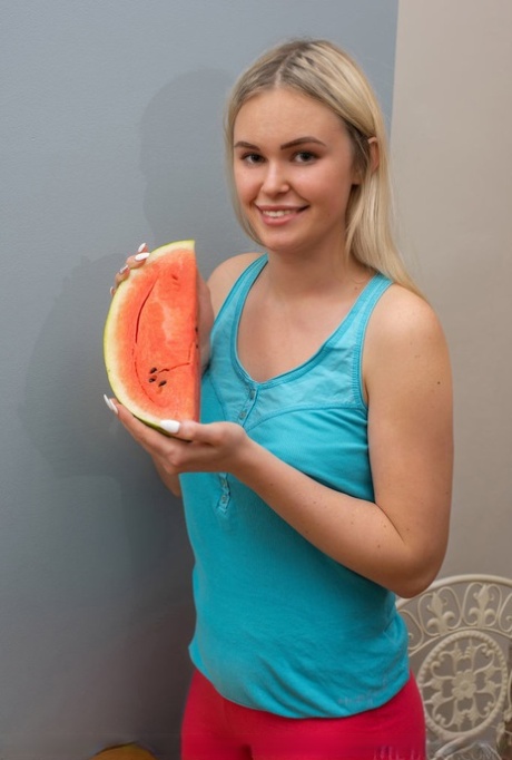 Junge blonde Ruth zerschneidet eine Wassermelone, bevor sie sich völlig nackt macht