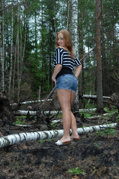 Pelirroja sexy muestra sus pequeñas tetas y su gran trasero mientras está en un bosque