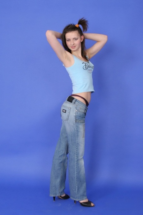 Brunette tiener gooit een tank top en jeans naar pose in haar underthings