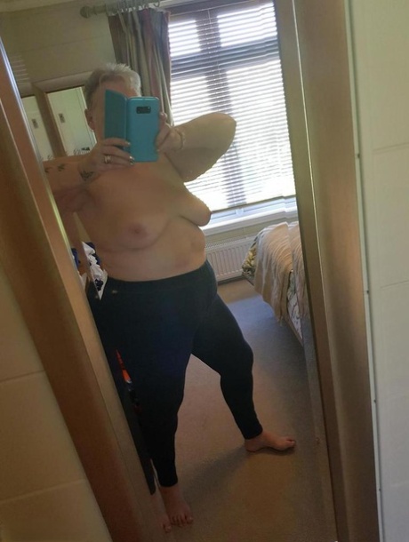 La pelirroja gorda nan Valgasmic Exposed posa desnuda sobre una cama en medias de nylon color canela y tacones