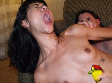 Adolescente asiática de pelo oscuro follada en un sofá por un chico caucásico