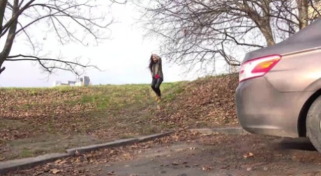 A rapariga caucasiana Esperansa faz chichi com urgência atrás de um carro estacionado