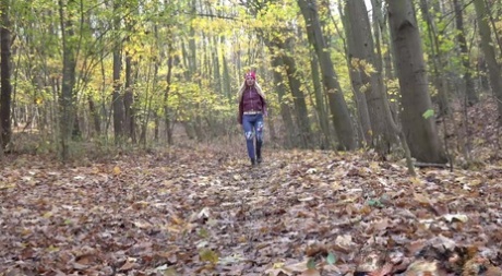 Blonda Caroli drar ner sina jeans för att kissa på löv i skogen