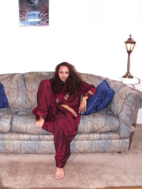 Una ragazza indiana sola si spoglia completamente su un divano a cassettoni