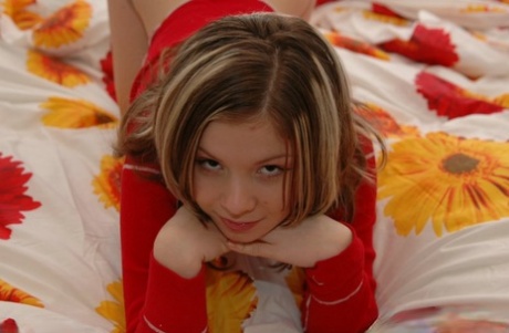 魅力的な少女が、赤い下着を身につけながらベッドの上でトップレスになる。