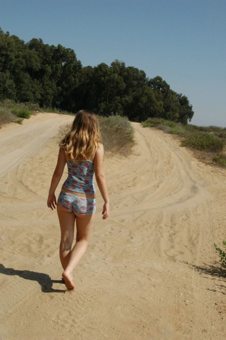 Sladká mladá dívka vystavuje svůj zadek praskliny, zatímco sám na polní cestě