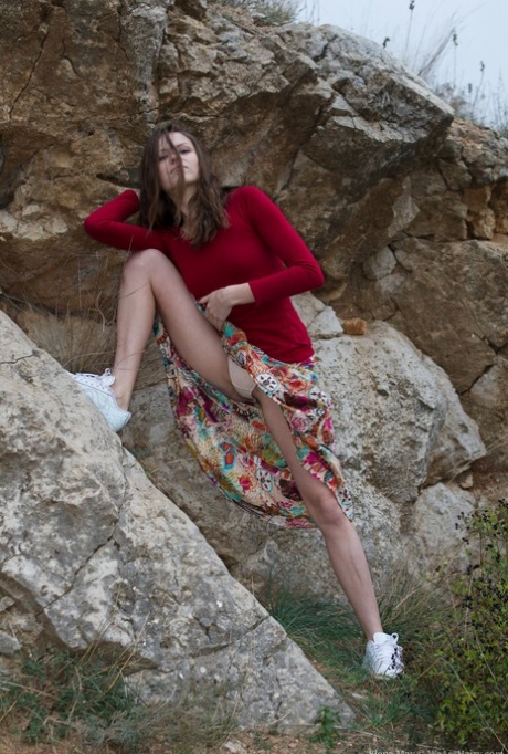Solo-Girl Elena May klettert eine Felswand, bevor sie ihre haarige Muschi spreizt
