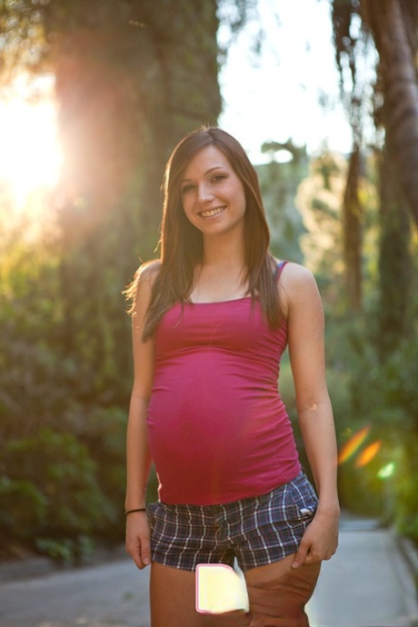 Zwanger meisje stript tot op haar verjaardagspakje op een stenen loopbrug