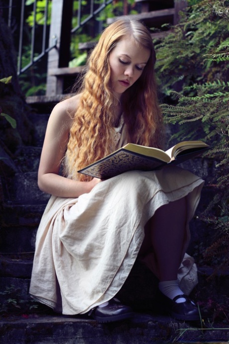 Den unga rödhåriga Dolly Little blottar sig på trädgårdstrappan medan hon läser
