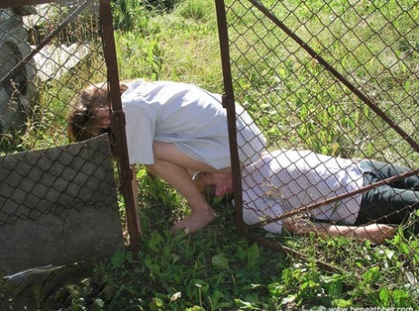 Chica caucásica a horcajadas sobre la cara de un hombre fuera de una caseta de perro en un patio