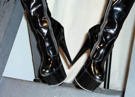 Dominant woman has a naked male slave lick her high heeled latex boots