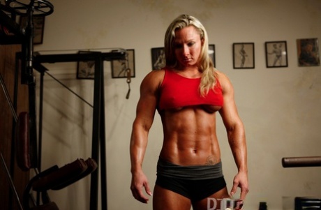 Blonde Bodybuilderin macht sich beim Training in Kniestrümpfen und Turnschuhen nackig