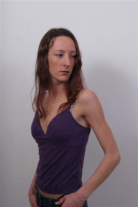 Tynn kvinne tar langsomt av seg klærne for å stå modell splitter naken.