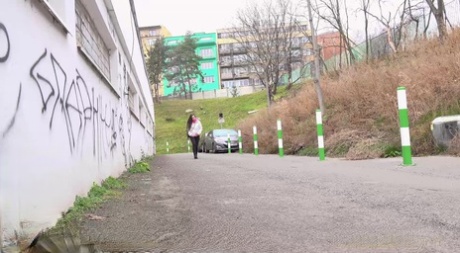 Lara Fox, una ragazza caucasica, si accovaccia su una strada asfaltata per fare la pipì che le serve.