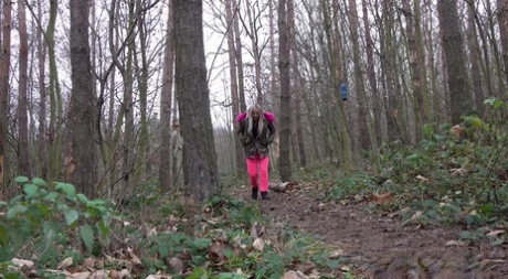 Une blonde sexy se tient debout et fait pipi dans la forêt.