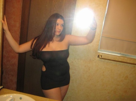 Curvy girl takes self shots in a mirror while wearing an off shoulder dress
