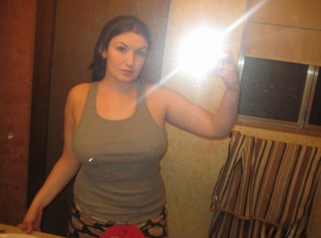 Une amatrice aux gros seins prend des selfies dans un miroir, sans danger pour le travail