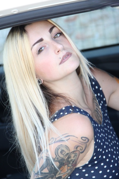 Татуированная девушка Medusa Blonde показывает свои голые ноги и задницу, находясь в машине