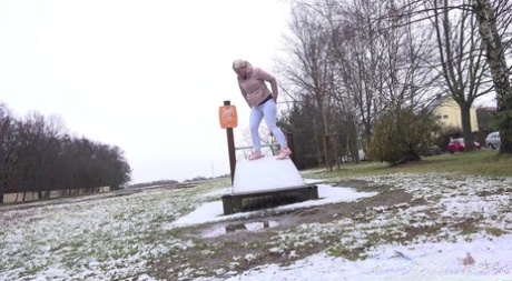 Blondes Mädchen Licky Lex pinkelt auf einer schneebedeckten Rutsche in einem Park