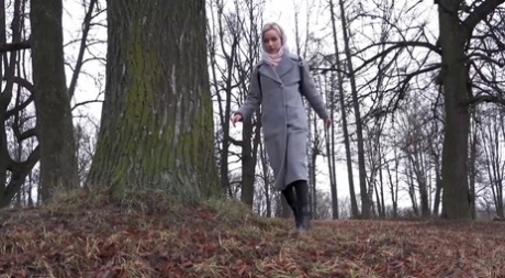 Blond meisje Masha doet een plasje voor een boom op een frisse dag