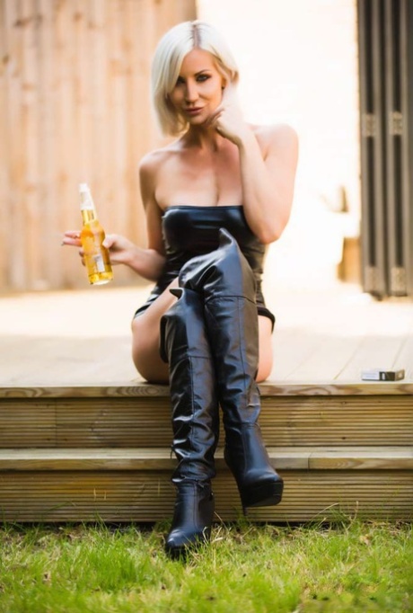 La blonde Jennifer Jade fume et boit dans des bottes de cuir au-dessus du genou.