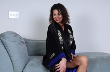 Ältere Amateurin Mimi Love spielt ihre rasierte Vagina in Fersen auf einem Sofa