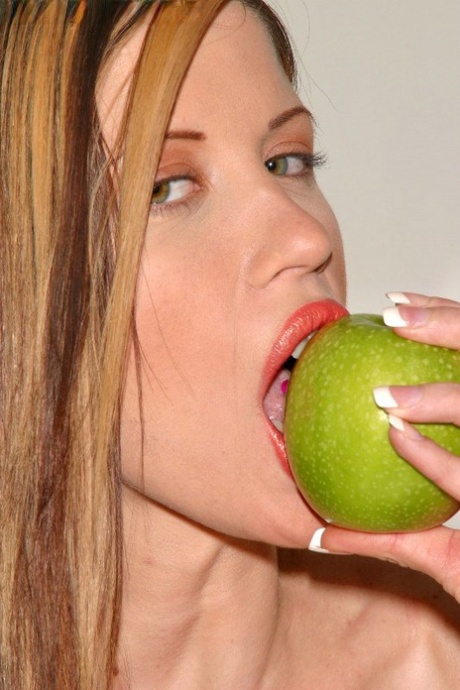 La modelo erótica Naudia de rodillas desnuda y tentadora con la manzana y el coño apretado