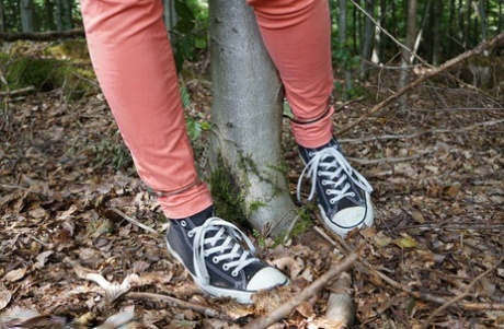 Clothed girl in canvas sneakers finds herself handcuffed to a tree in woods