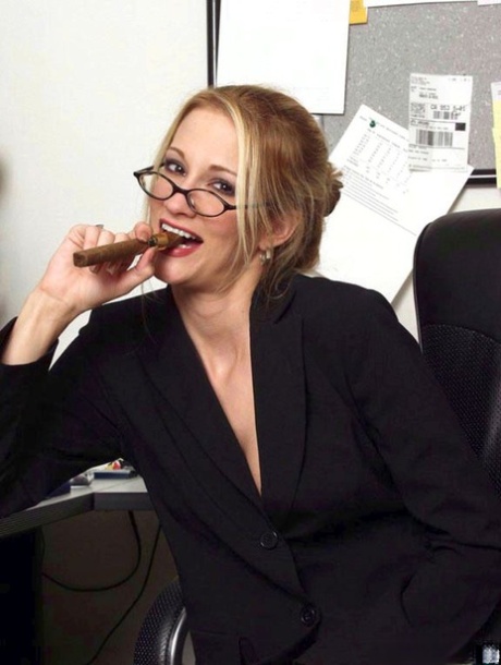 La secretaria de piernas largas Jessica Drake se suelta el pelo antes de masturbarse en su escritorio