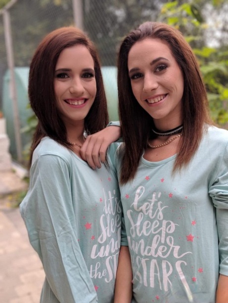 As raparigas gémeas tiram fotos a si próprias enquanto vestidas e em lingerie