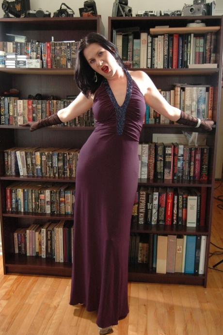 Amatørmodellen Mina Gorey stripper nøgen i handsker og høje hæle foran en bogreol