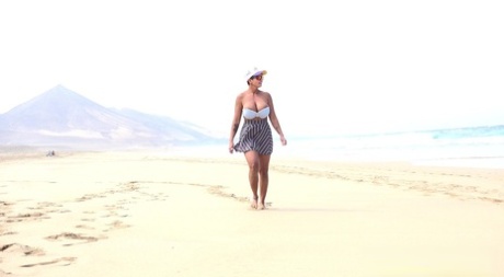 Chloe, una donna caucasica, piscia mentre passeggia su una spiaggia deserta.
