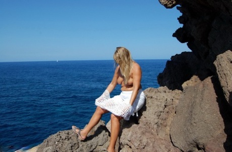 La rubia amateur Sweet Susi expone sus tetas y culo en unas rocas junto al mar