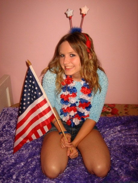 Cute teen holds an American flag while saluting after a finger fuck