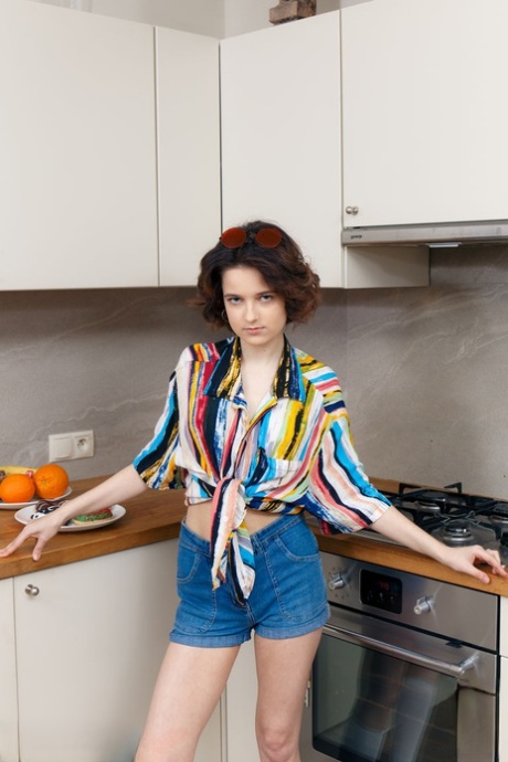 Teenage-solopigen Polyna er nøgen i køkkenet, mens hun spiser donuts