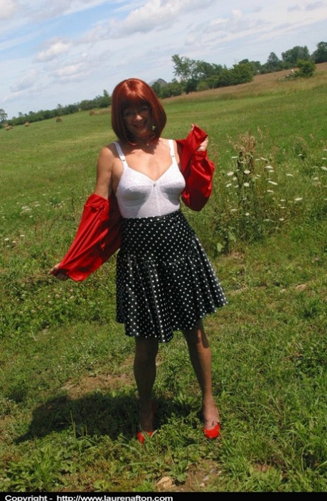 Äldre rödhåriga Lauren modellerar en retro gördel och nylonstrumpor på ett fält
