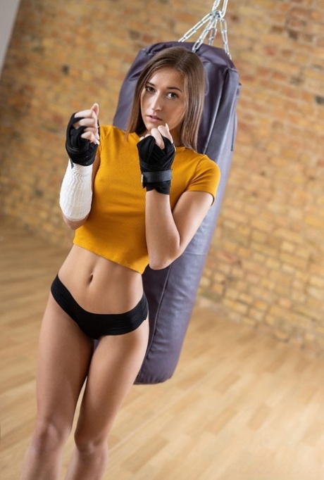 Adolescente descalça toca na sua bela rata depois de uma sessão com um saco de boxe