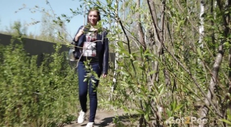 De verontruste vrouw Viktoria neemt een broodnodige plas op een spiegel te midden van struiken