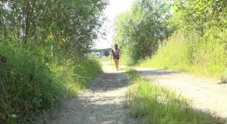 Jena Lovely zeigt ihre kahle Muschi, während sie sich zum Pissen auf einen Feldweg hockt