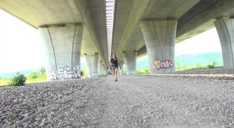 Den blonde pige Jenna Lovely tisser under en viadukt