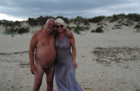 Oudere platinablonde Dimonty zoent terwijl ze op een naaktstrand is met haar man