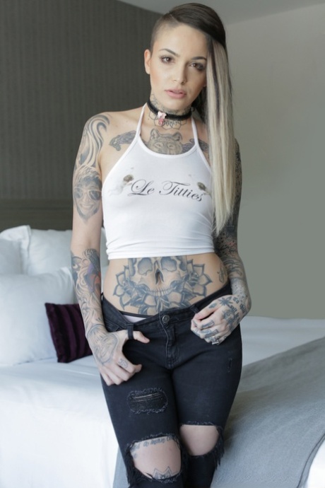 Tattooed girl Leigh Raven wears a black choker while getting naked