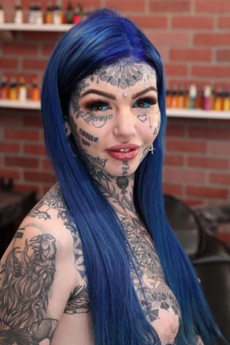 Den stærkt tatoverede pige Amber Luke poserer nøgen i en tatoveringsbutik