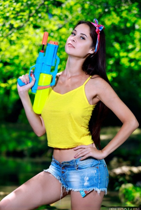 Young brunette Martina Mink wields a water gun while getting naked by a brook